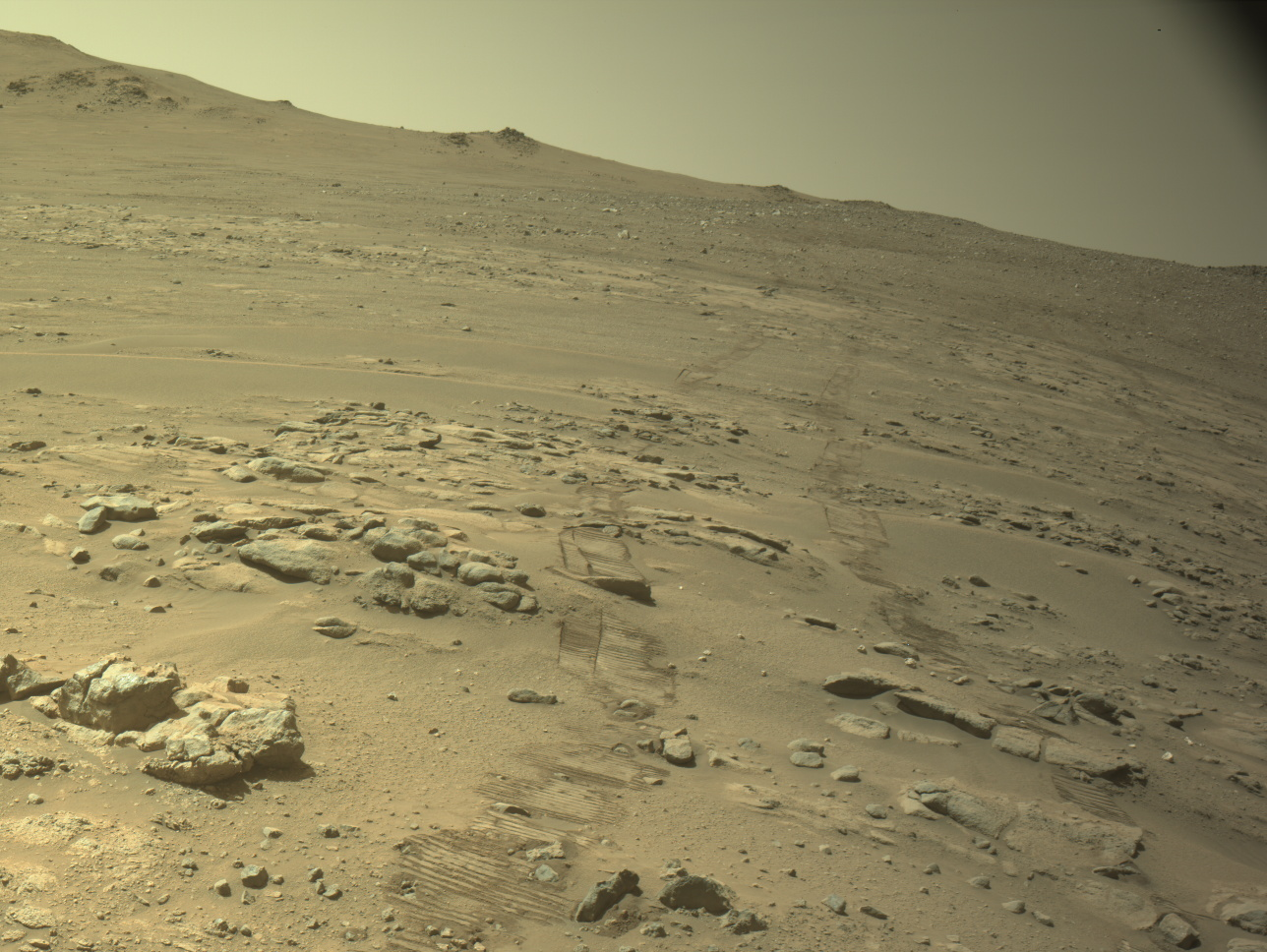 Real navigation-camera photograph of Perseverance's wheel tracks crossing the rocky Martian terrain